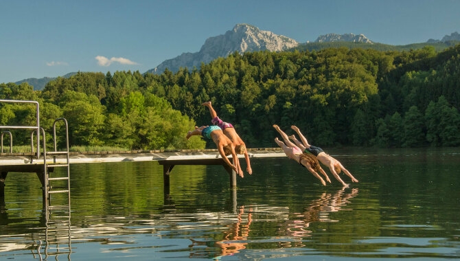 Kinder beim springen ins Wasser von einem Steg.
