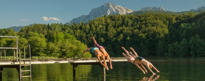 Kinder beim springen ins Wasser von einem Steg