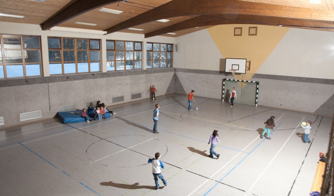 Blick von oben in die Turnhalle des Haus Chiemgau mit spielenden Kindern.