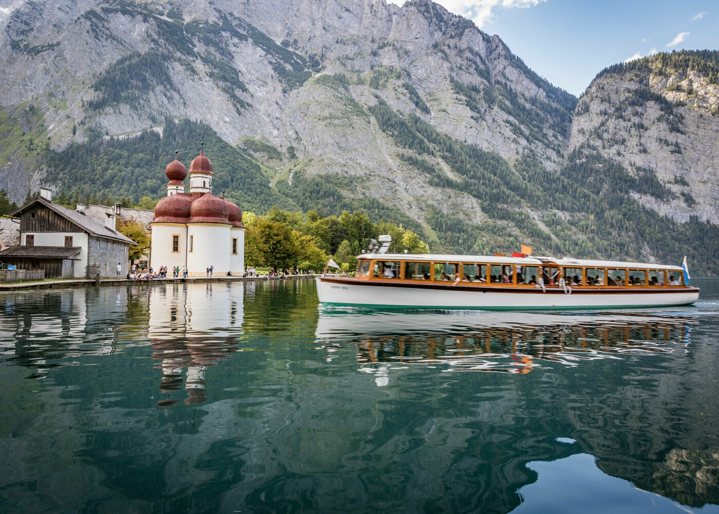 Boot am Königssee mit den Bergen im Hintergrund und kleinem Ort auf der linken Seite